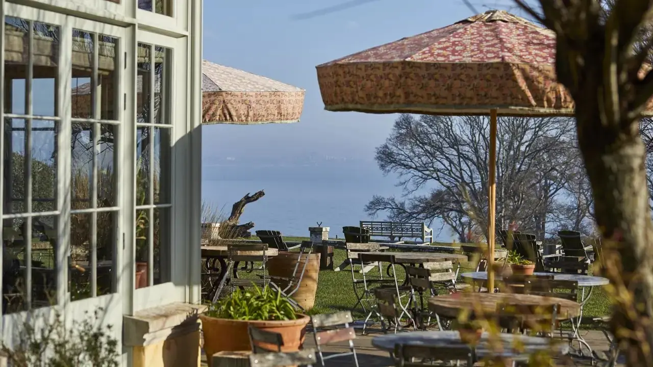 The conservatory terrace with patterned parasols and garden tables, looking out over Studland Bay